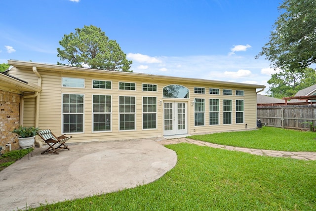 rear view of house with a lawn, a patio, fence, and french doors