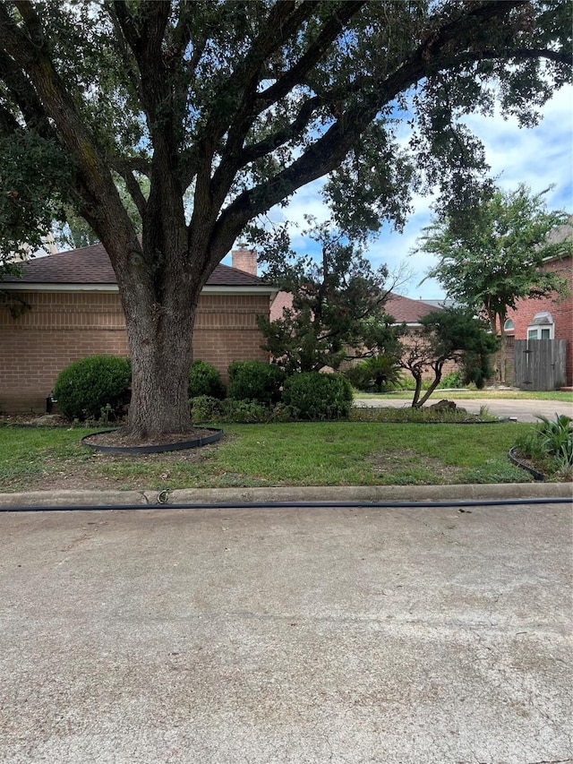 view of side of home featuring brick siding, fence, and a chimney