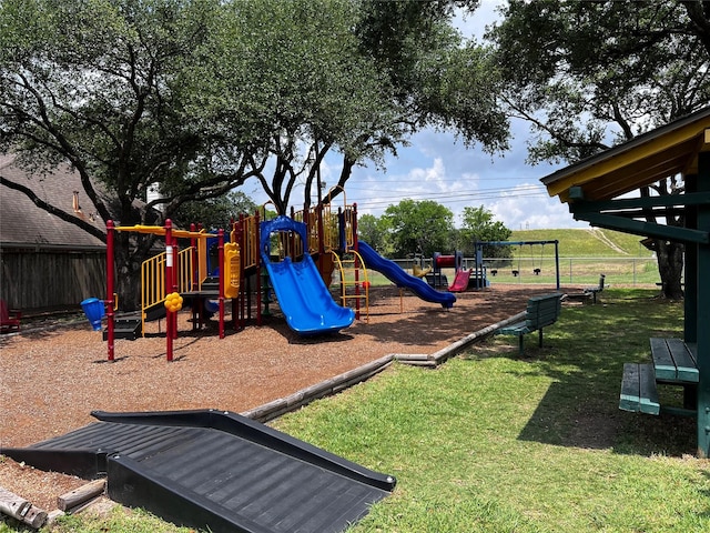 community play area featuring a lawn and fence