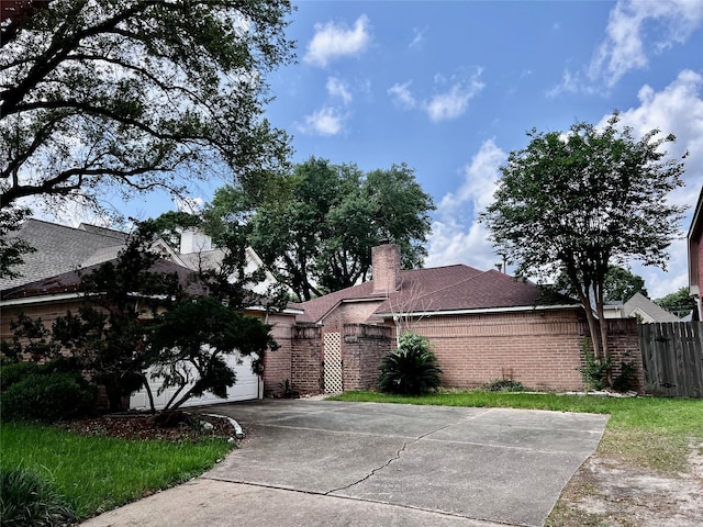 ranch-style house featuring fence, a chimney, driveway, and brick siding