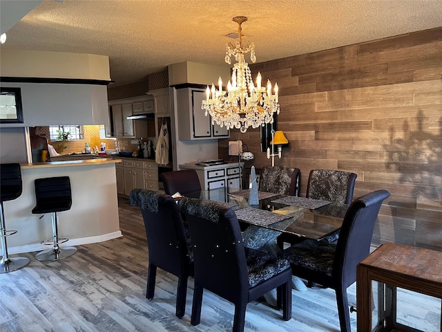 dining area with a chandelier, a textured ceiling, wood walls, and wood finished floors