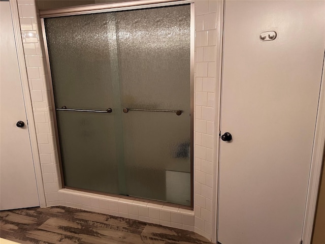 full bathroom featuring a shower stall and wood finished floors