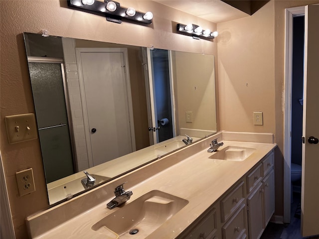 bathroom featuring double vanity, a shower stall, and a sink
