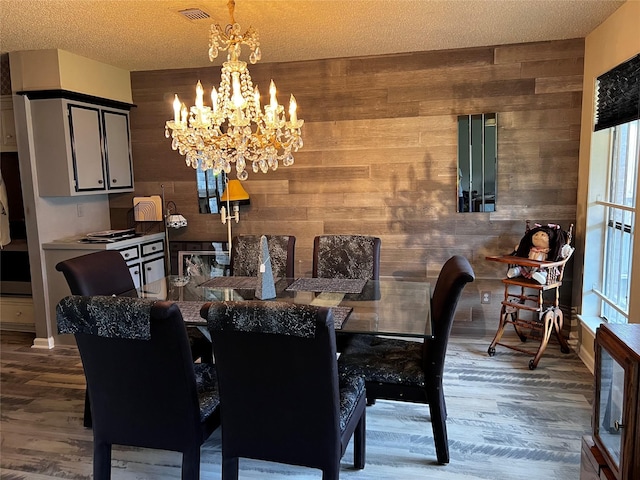 dining area featuring wooden walls, a chandelier, and visible vents