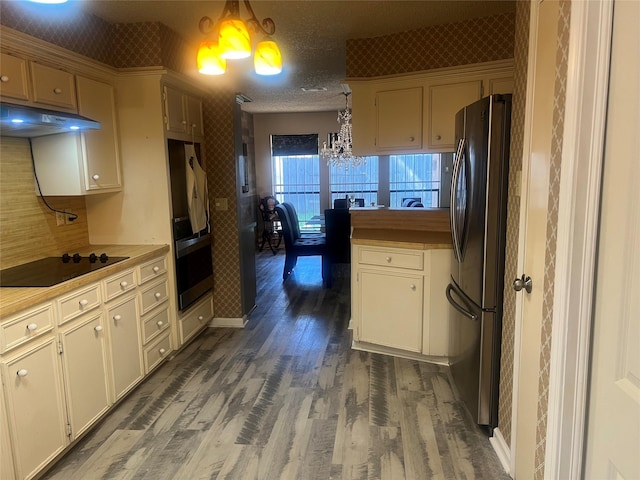 11726 Pecan Creek Dr, Houston, TX 77043 - kitchen featuring freestanding refrigerator, under cabinet range hood, black electric cooktop, a chandelier, and wood finished floors