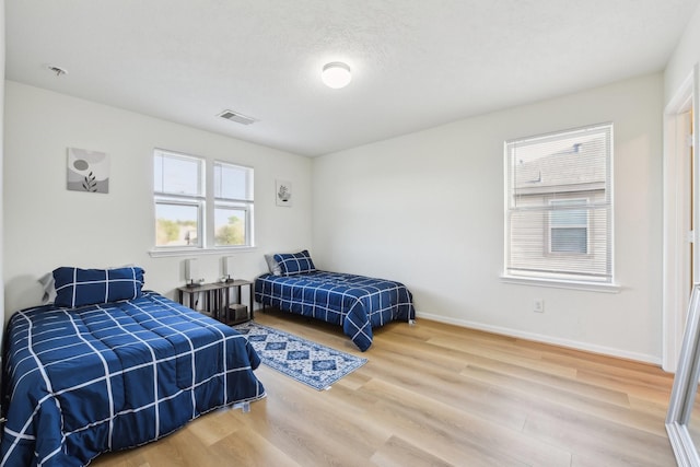 bedroom featuring baseboards, wood finished floors, and visible vents