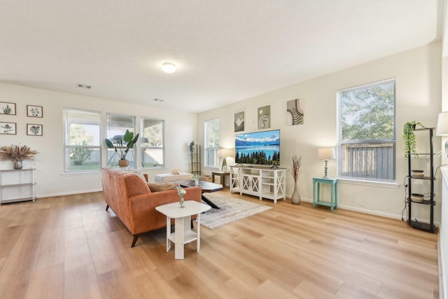 living room featuring baseboards, light wood-type flooring, and visible vents