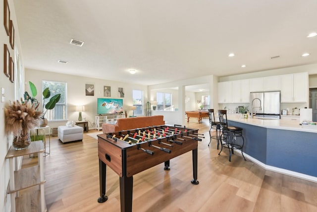 rec room featuring light wood-style floors, recessed lighting, a sink, and visible vents