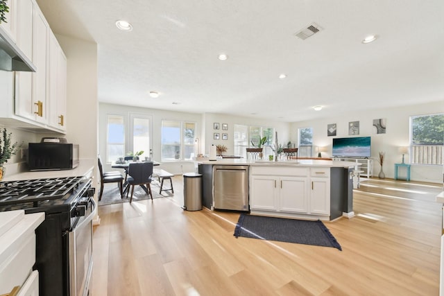 kitchen featuring open floor plan, light wood-type flooring, recessed lighting, white cabinets, and appliances with stainless steel finishes