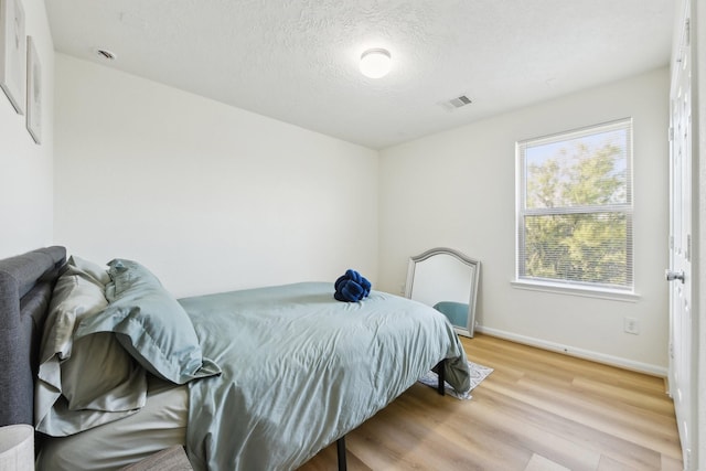 bedroom with visible vents, baseboards, and wood finished floors