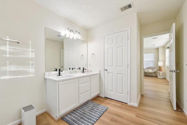 bathroom featuring visible vents, a sink, and wood finished floors
