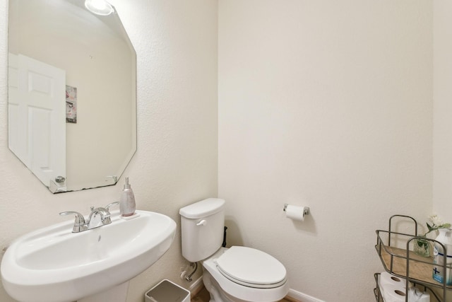 bathroom with a sink, baseboards, and toilet