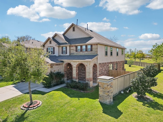 view of front of house with stone siding, fence, driveway, and a front yard