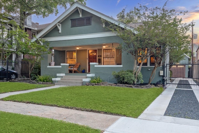 view of front facade with a porch, fence, a gate, and stucco siding
