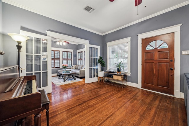 entrance foyer featuring visible vents, crown molding, wood finished floors, a healthy amount of sunlight, and a ceiling fan