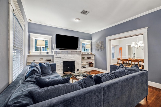 living area with visible vents, ornamental molding, wood finished floors, baseboards, and a chandelier