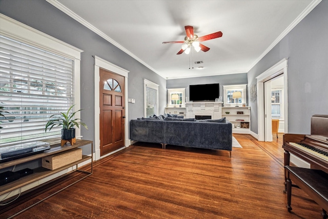 living room with ornamental molding, wood finished floors, a fireplace, baseboards, and ceiling fan