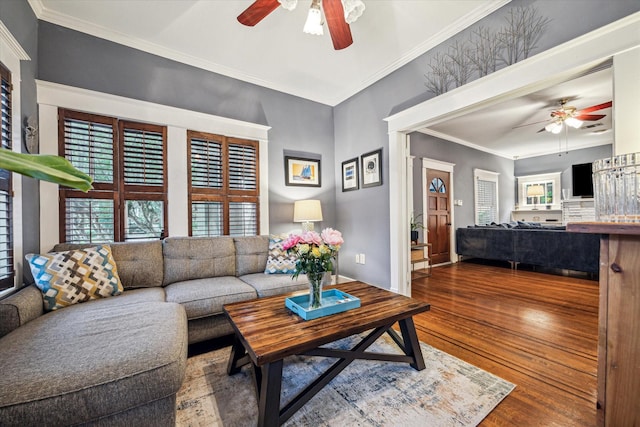 living room with baseboards, ceiling fan, ornamental molding, and wood finished floors
