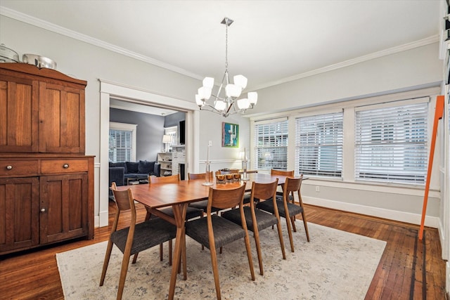 dining space with crown molding, dark wood-style flooring, baseboards, and a notable chandelier