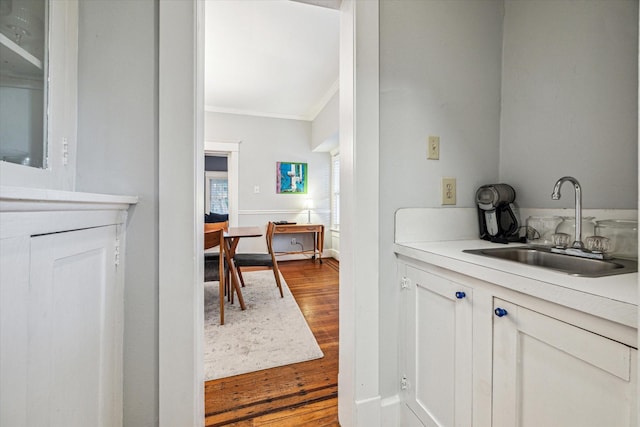 bar featuring a sink, crown molding, and dark wood-type flooring