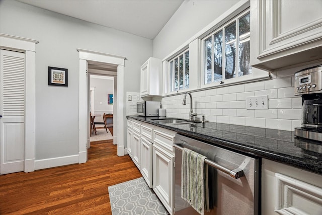 kitchen featuring decorative backsplash, dark wood-style flooring, a sink, dark stone countertops, and stainless steel appliances