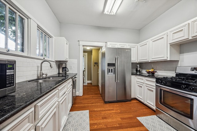 kitchen with a sink, decorative backsplash, appliances with stainless steel finishes, and white cabinets