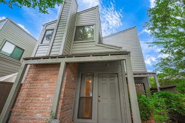 view of exterior entry with brick siding and a chimney