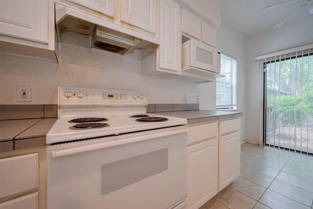 kitchen with white appliances, white cabinets, under cabinet range hood, and light tile patterned floors
