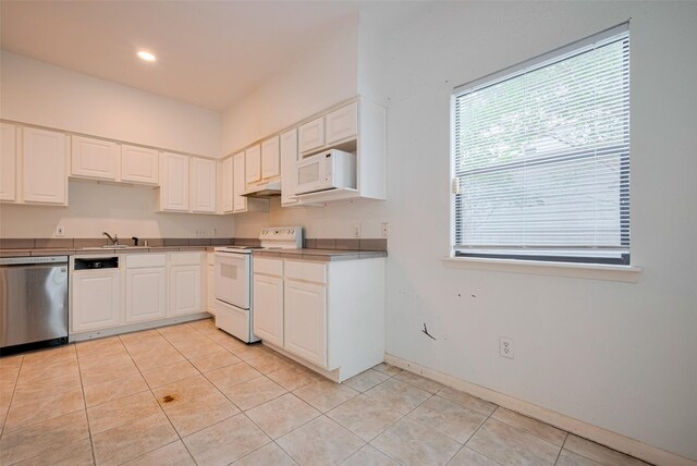 kitchen featuring white cabinetry, light tile patterned floors, under cabinet range hood, and white appliances