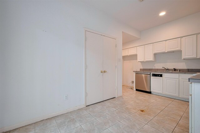 kitchen with white cabinets, dark countertops, recessed lighting, light tile patterned floors, and stainless steel dishwasher