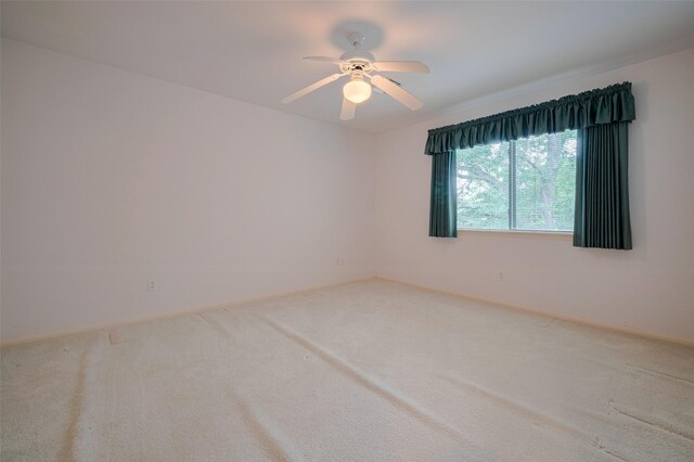 empty room featuring baseboards, carpet flooring, and ceiling fan