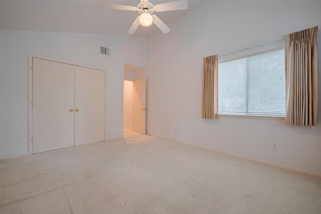 unfurnished bedroom with carpet floors, high vaulted ceiling, a ceiling fan, visible vents, and a closet