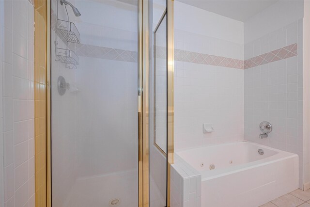 full bath featuring a tub with jets, tile patterned flooring, and a stall shower