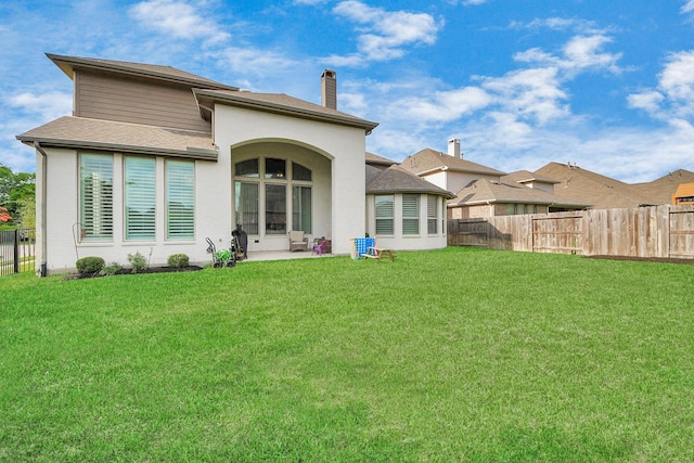 back of property featuring a fenced backyard, a chimney, and a yard