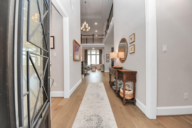 entrance foyer with light wood-type flooring, baseboards, and an inviting chandelier