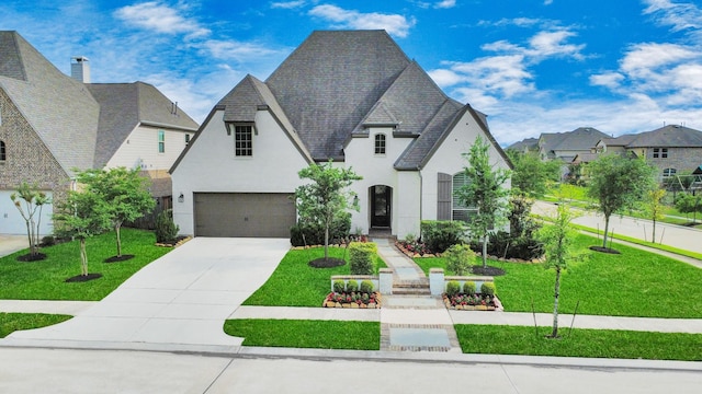 french provincial home with stucco siding, driveway, and a front lawn