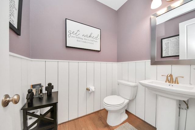 bathroom with toilet, a sink, wainscoting, and wood finished floors