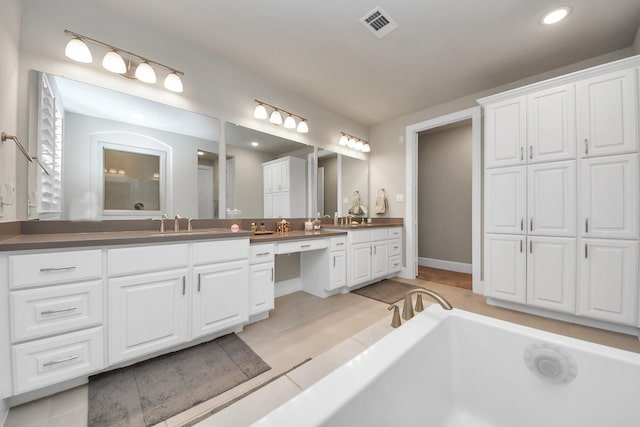 full bath with a sink, double vanity, a bathtub, recessed lighting, and visible vents