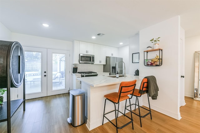4110 Lou Anne Ln, Houston, TX 77092 - kitchen featuring stainless steel appliances, light wood-style floors, a breakfast bar, a peninsula, and recessed lighting