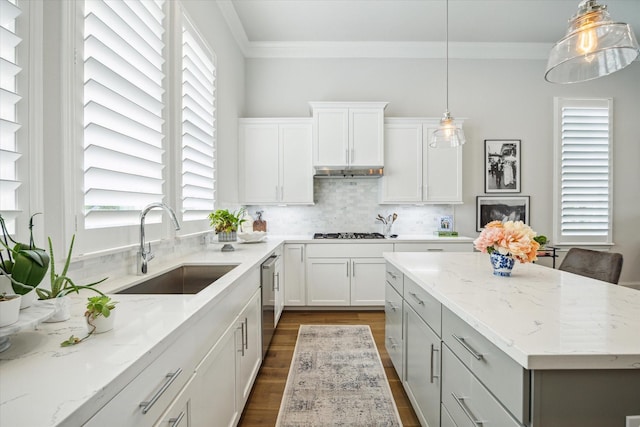 kitchen with gas cooktop, a sink, light stone counters, ornamental molding, and dark wood-type flooring