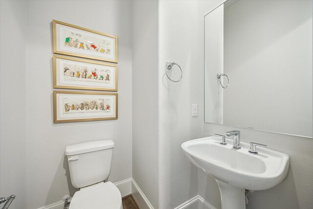 bathroom featuring toilet, baseboards, and a sink