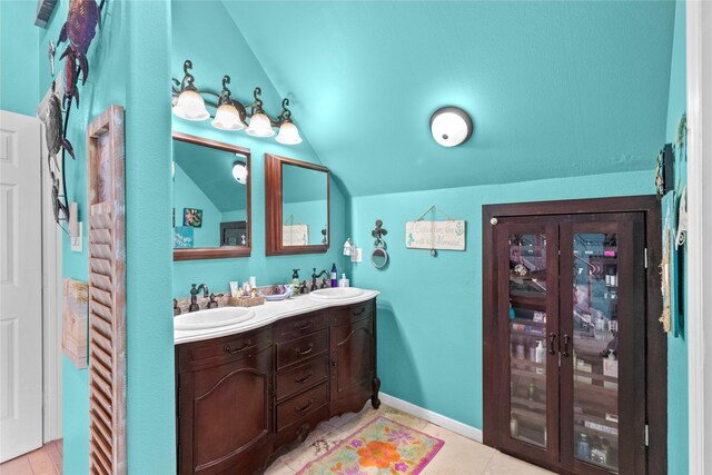 full bathroom featuring double vanity, tile patterned floors, vaulted ceiling, and a sink