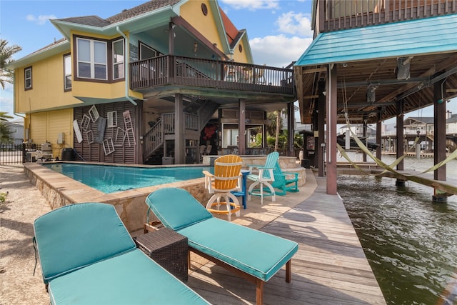 rear view of property with stairs, an outdoor pool, boat lift, and a deck