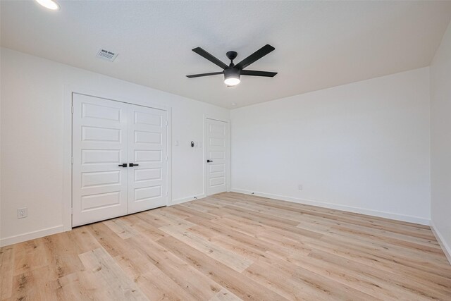 unfurnished bedroom with a ceiling fan, visible vents, light wood-type flooring, baseboards, and a closet