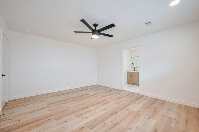 spare room with light wood-style floors, baseboards, a ceiling fan, and visible vents
