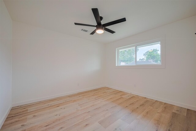 unfurnished room featuring a ceiling fan, baseboards, visible vents, and wood finished floors