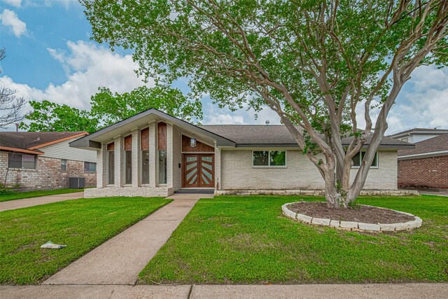 mid-century home with brick siding, a front lawn, and cooling unit