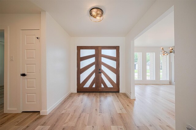entrance foyer with an inviting chandelier, light wood finished floors, and baseboards