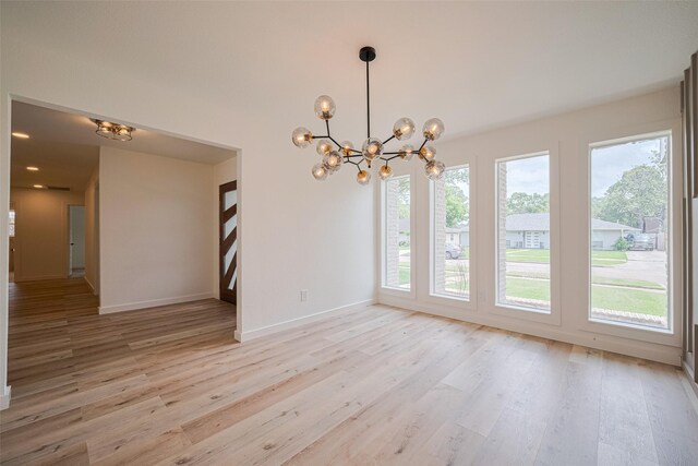 unfurnished dining area with baseboards, light wood-type flooring, and a chandelier