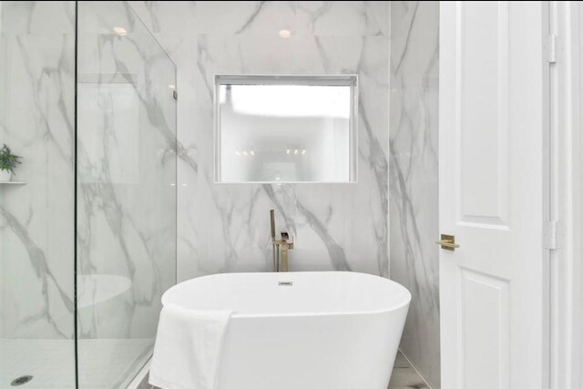 bathroom with a marble finish shower and a soaking tub